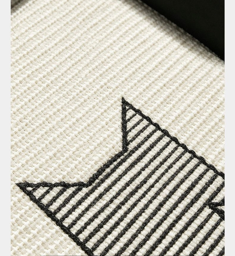 Close-up of embroidered cat silhouette on cream woven sisal-look fabric with black bolster