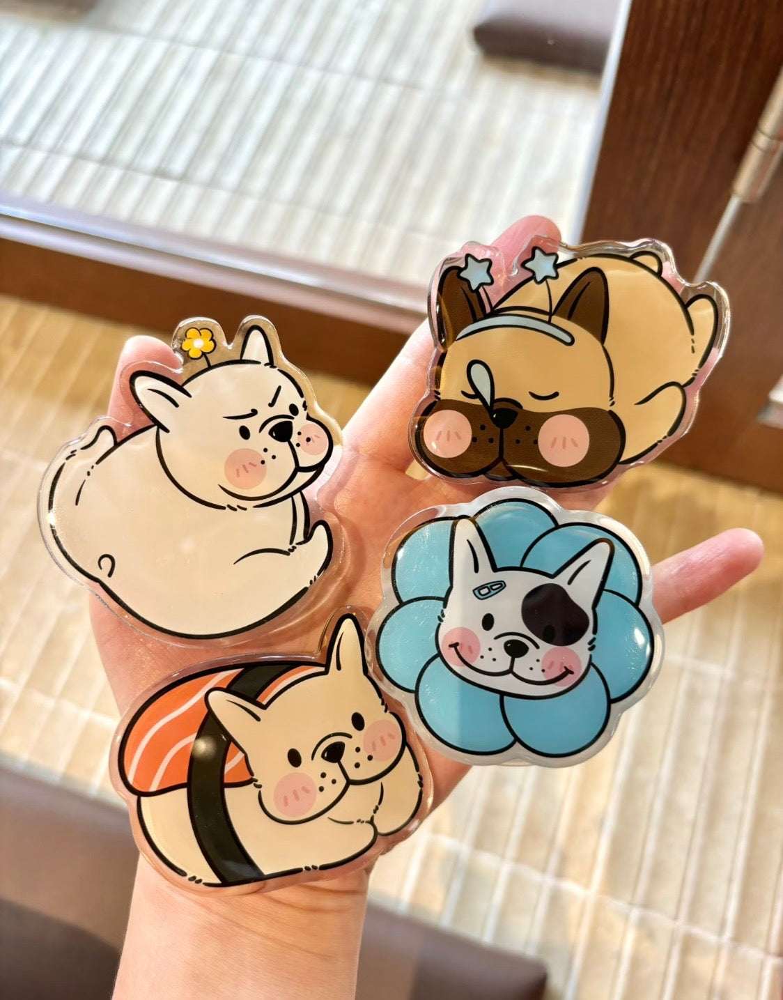 Hand holding four cute Frenchie acrylic phone grips